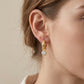Close-up view of a model wearing classic gold tubular hoop earrings with round moissanite drop charm.