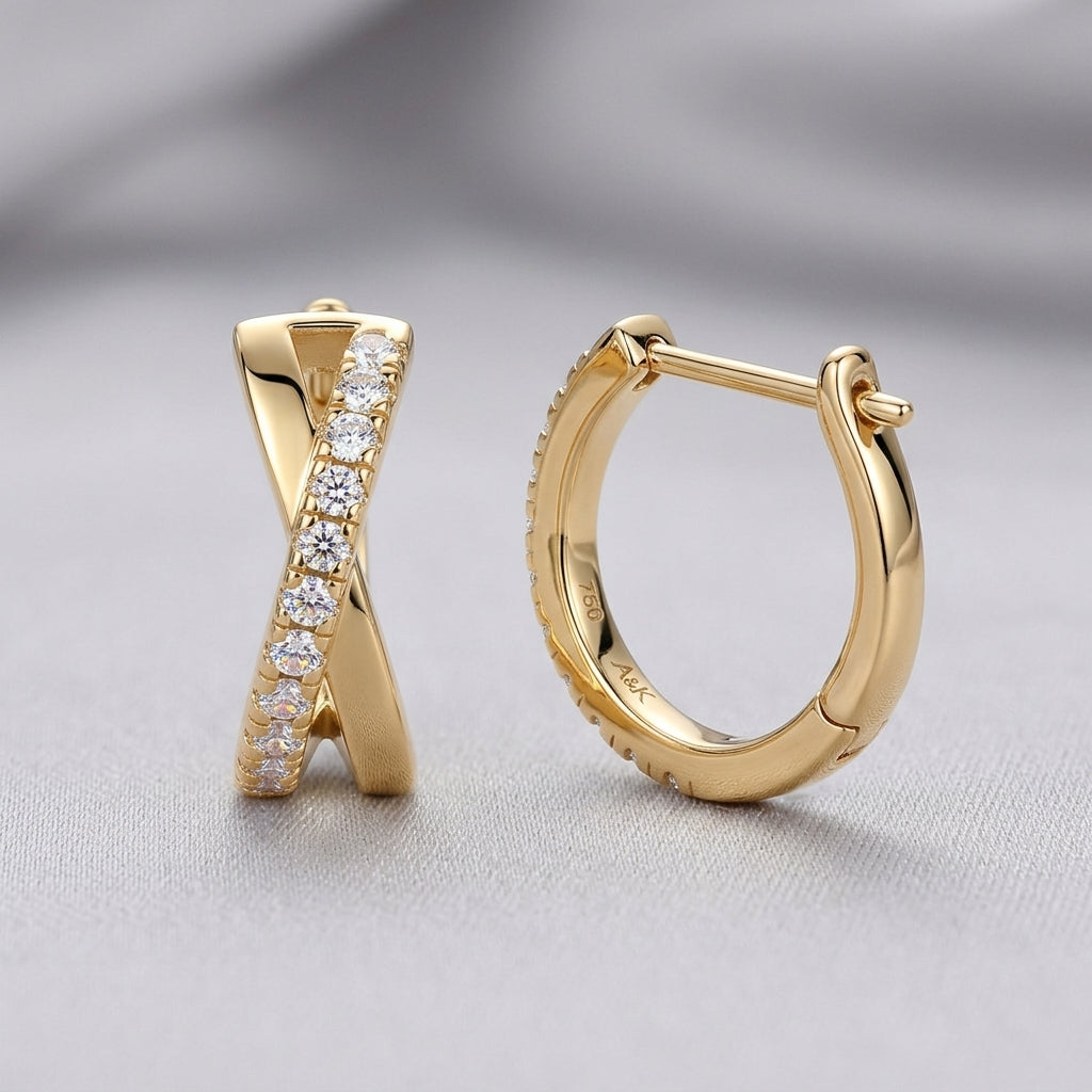 Gold X-shaped huggie earrings with pavé moissanite displayed on a gray background.