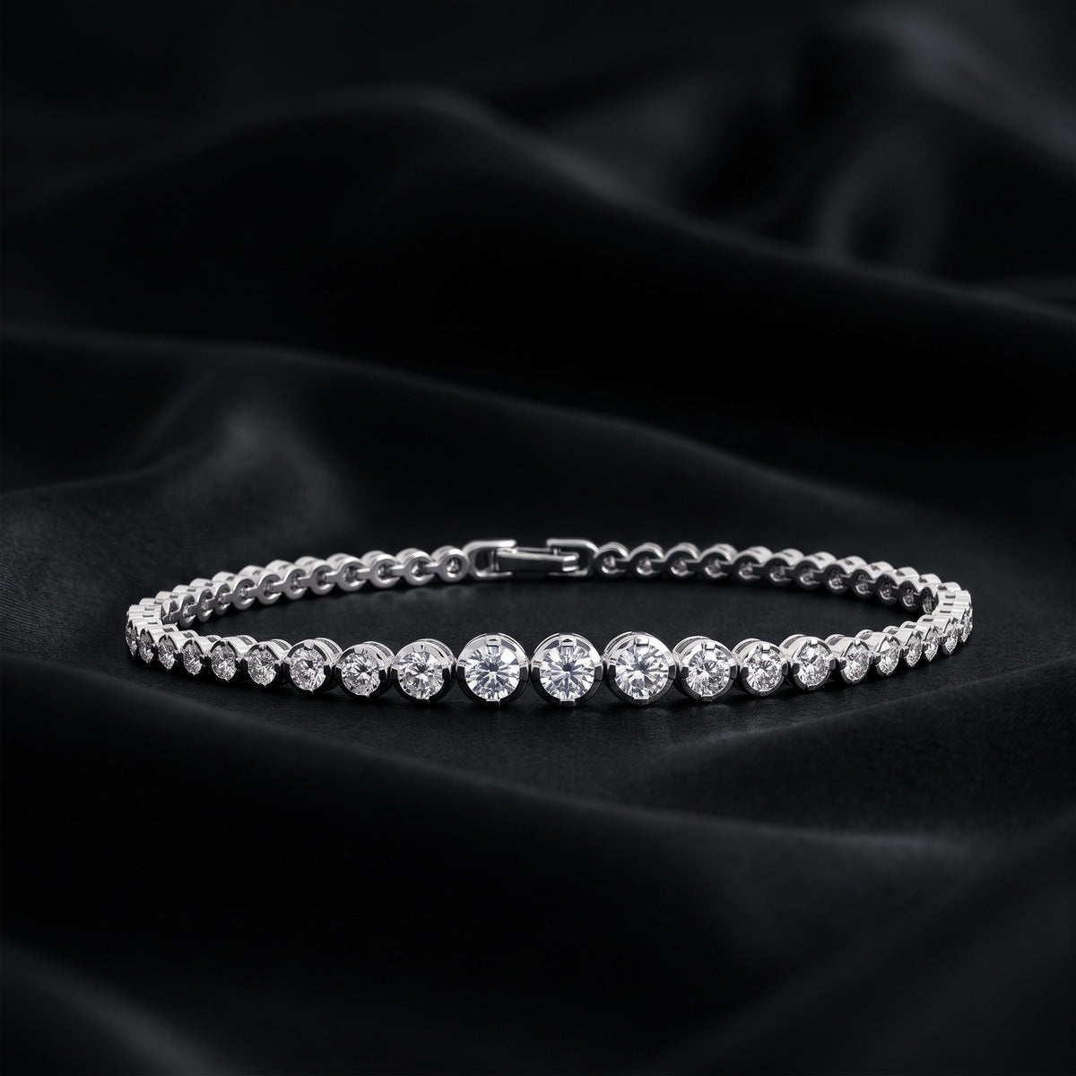 Full circle view of graduated bezel round lab-grown diamond tennis bracelet on dark silk.