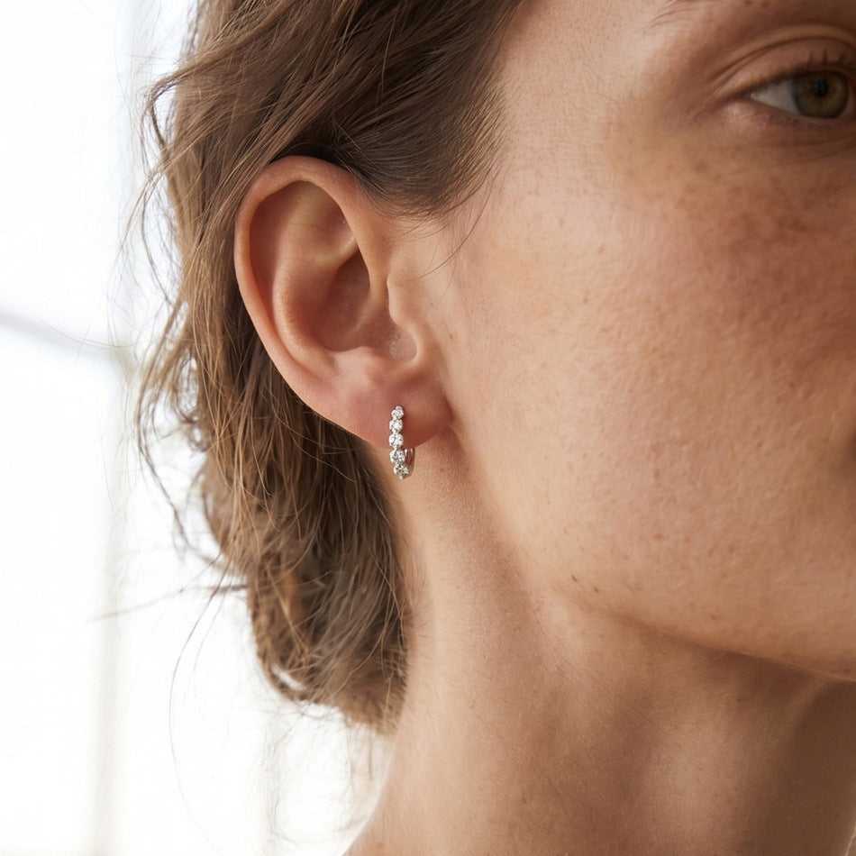 Model wearing graduated lab-grown diamond journey huggie hoops earrings.
