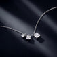 Graduated moissanite trio square drop necklace on dark blue silk background.