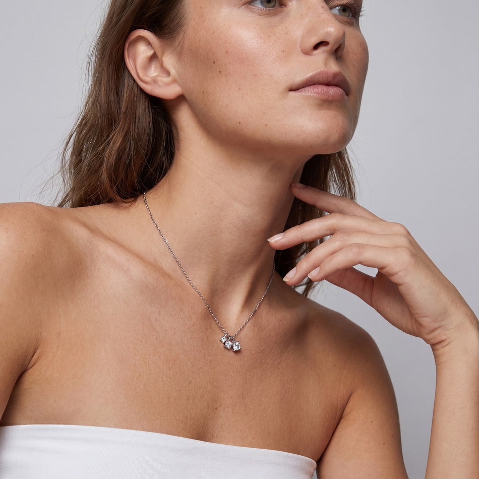 Model wearing graduated moissanite trio square drop pendant necklace on collarbone.