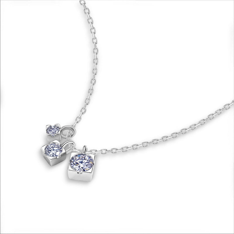 Perspective view of graduated moissanite trio square drop pendant necklace on white background.