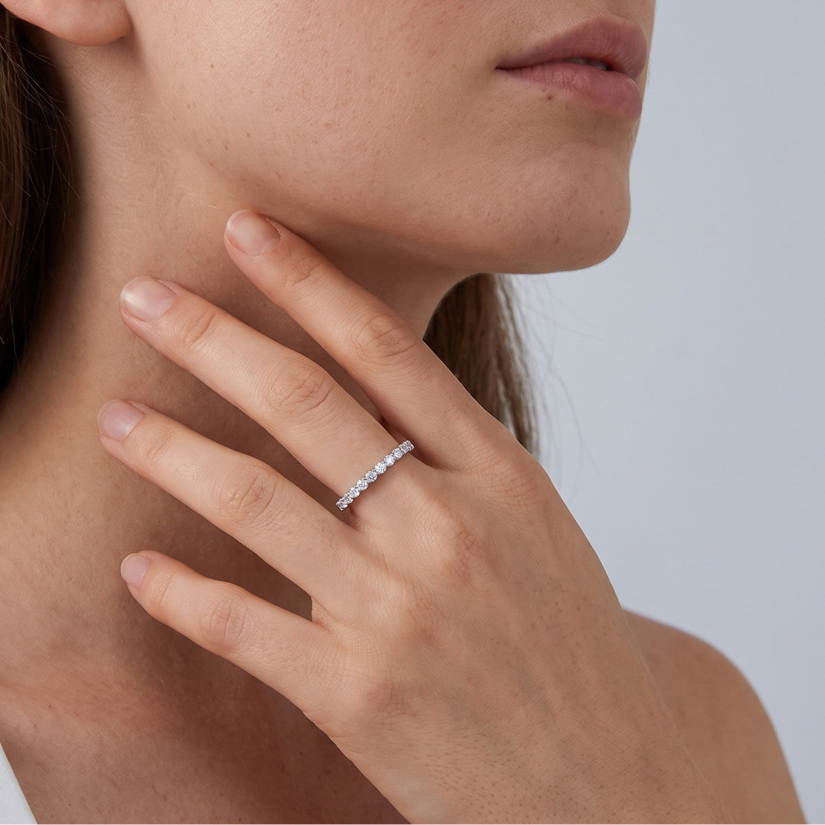 Woman wearing delicate half eternity lab grown diamond stacking ring on finger