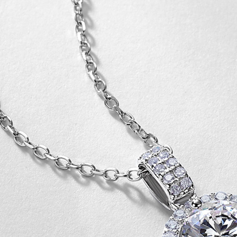 Close-up view of double-row micro-pave bail and cable chain on round halo diamond pendant.