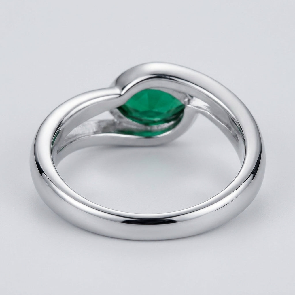 Studio product view focusing on the sleek gallery profile and inner band of a handcrafted bezel-set emerald solitaire ring.