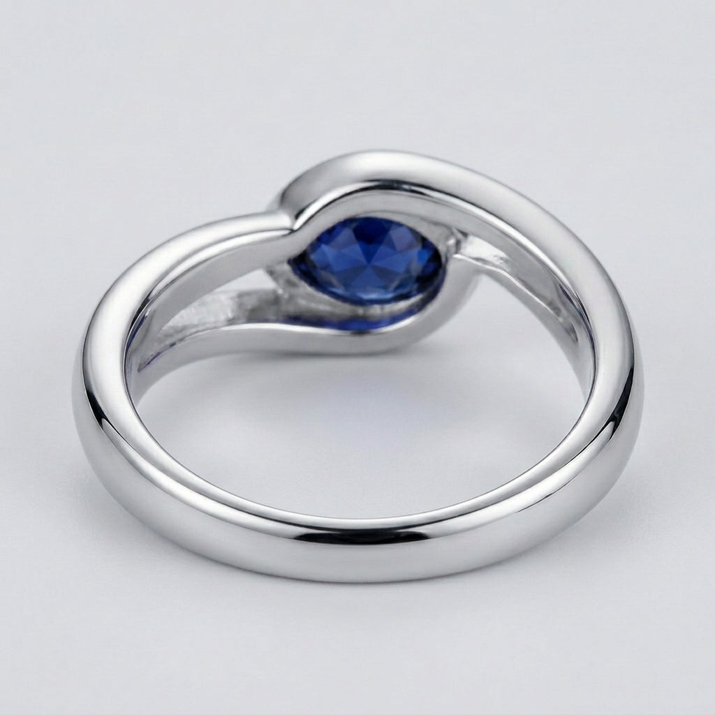 Studio product view focusing on the sleek gallery profile and inner band of a handcrafted bezel-set blue sapphire solitaire ring.
