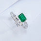 Three-quarter studio product profile focusing on the open-band architecture of a handcrafted bypass emerald solitaire ring.