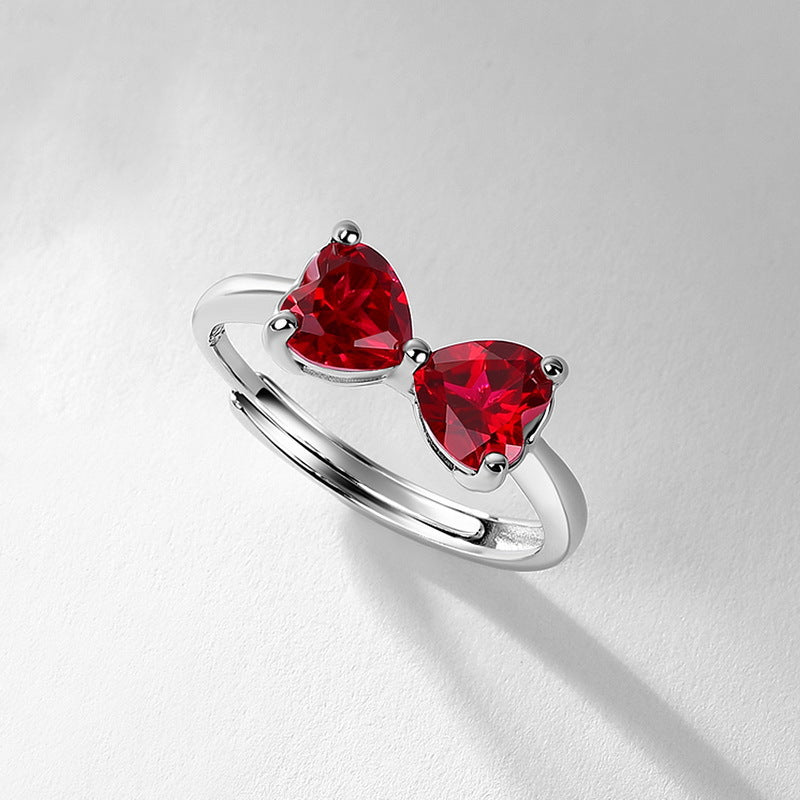 Diagonal overhead studio view of a handcrafted double-heart ruby adjustable ring casting a soft gradient shadow.	Ruby Bow Ring - Detail