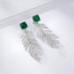 High-angle perspective view of a pair of handcrafted lab-grown emerald wheat chandelier earrings with crisp shadows.