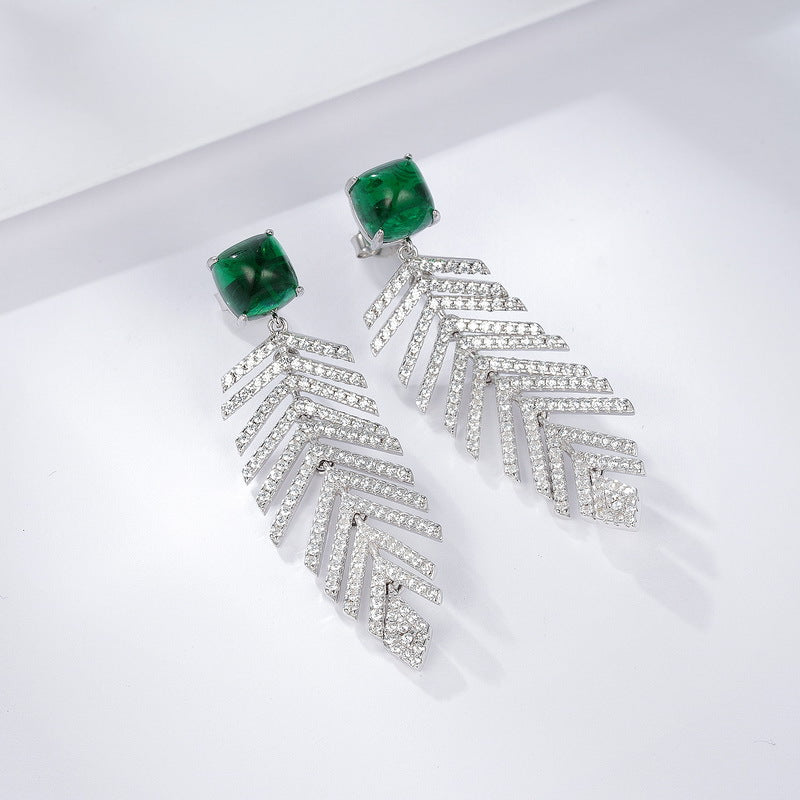 High-angle perspective view of a pair of handcrafted lab-grown emerald wheat chandelier earrings with crisp shadows.