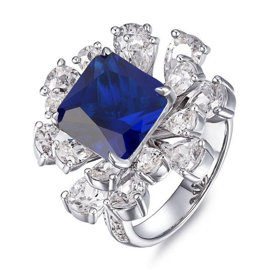 Three-quarter studio shot of a luxury asscher-cut blue sapphire floral cluster statement ring with a polished shank.
