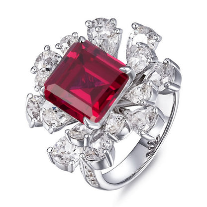 White background close-up product shot of a handcrafted pave-set diamond asscher ruby floral cluster ring.