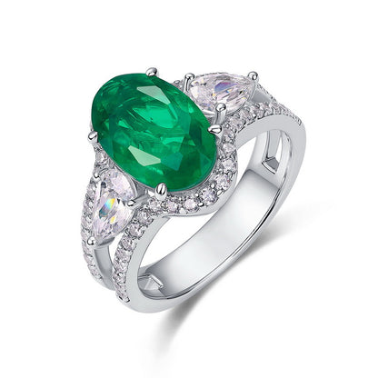 White background front view showcasing a handcrafted pave-diamond encrusted oval emerald statement halo ring.