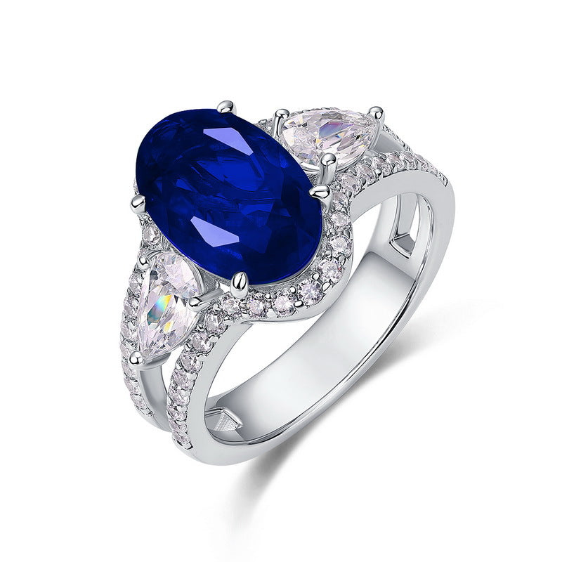 White background front view showcasing a handcrafted pave-diamond encrusted oval sapphire statement halo ring.