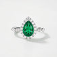 White background front view showcasing a handcrafted pear-cut emerald solitaire halo ring with an Art Deco pave band.