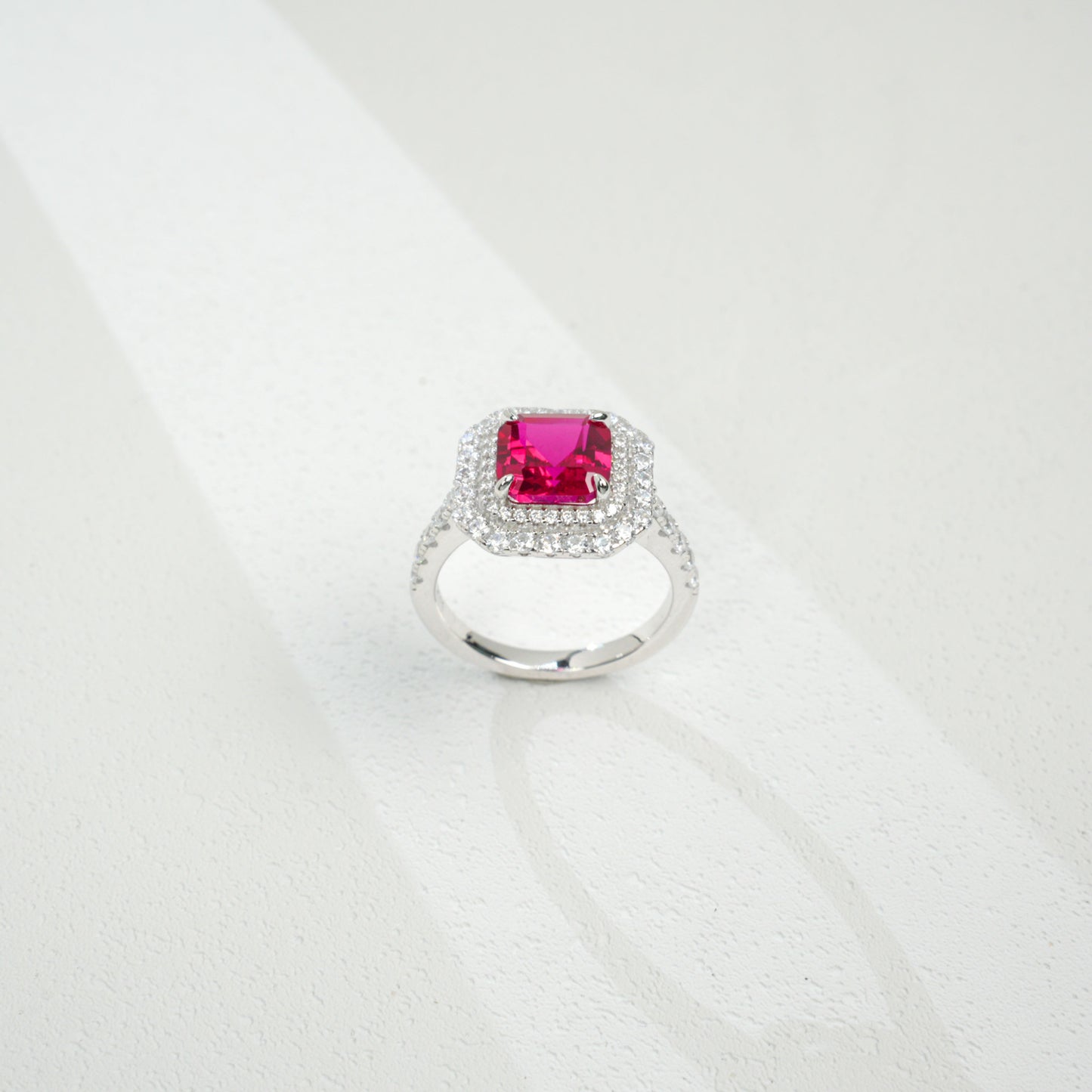 Top-down studio shot showcasing a handcrafted pigeon blood ruby double halo cocktail ring casting a gradient shadow.