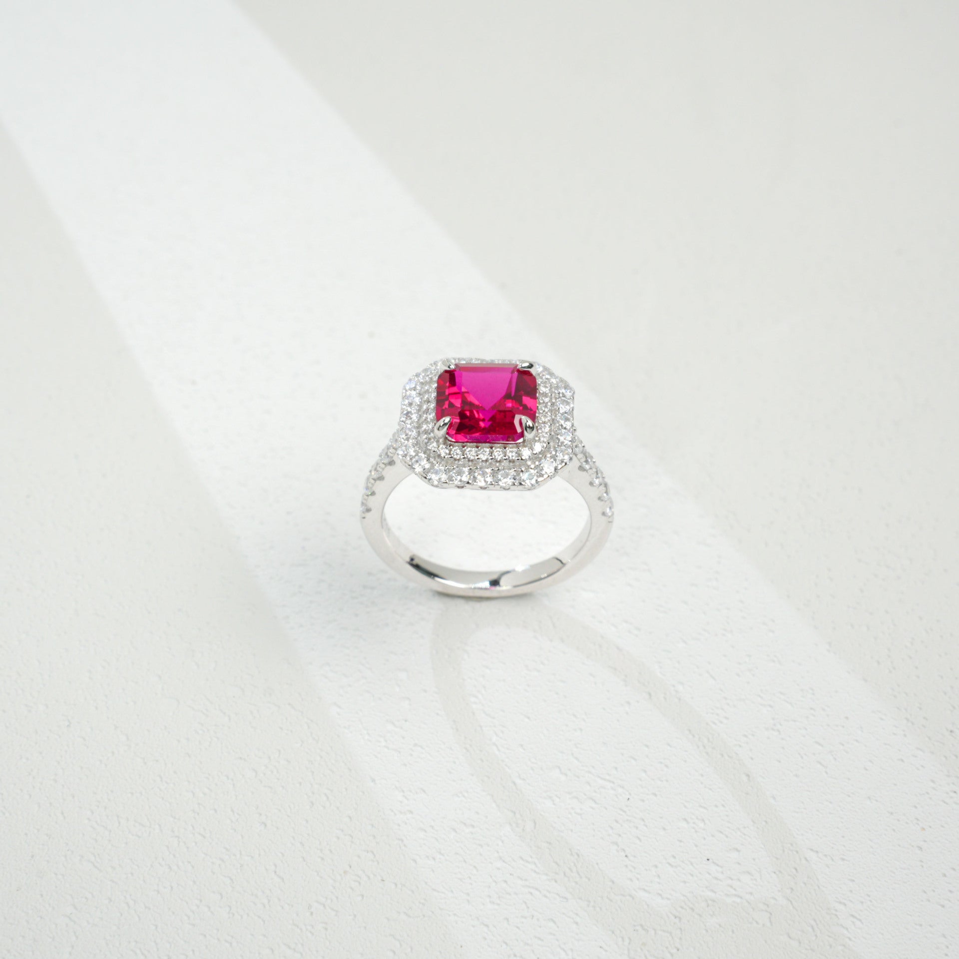 Top-down studio shot showcasing a handcrafted pigeon blood ruby double halo cocktail ring casting a gradient shadow.