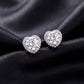 Pair of heart halo round cut lab grown diamond stud earrings resting on dark black silk