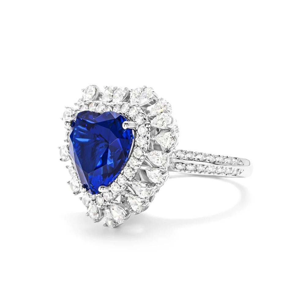 Ring with a heart-shaped blue gemstone and diamond accents on a white background