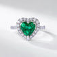White background product view of an elegant heart-shaped emerald engagement ring in white gold or silver pave band.