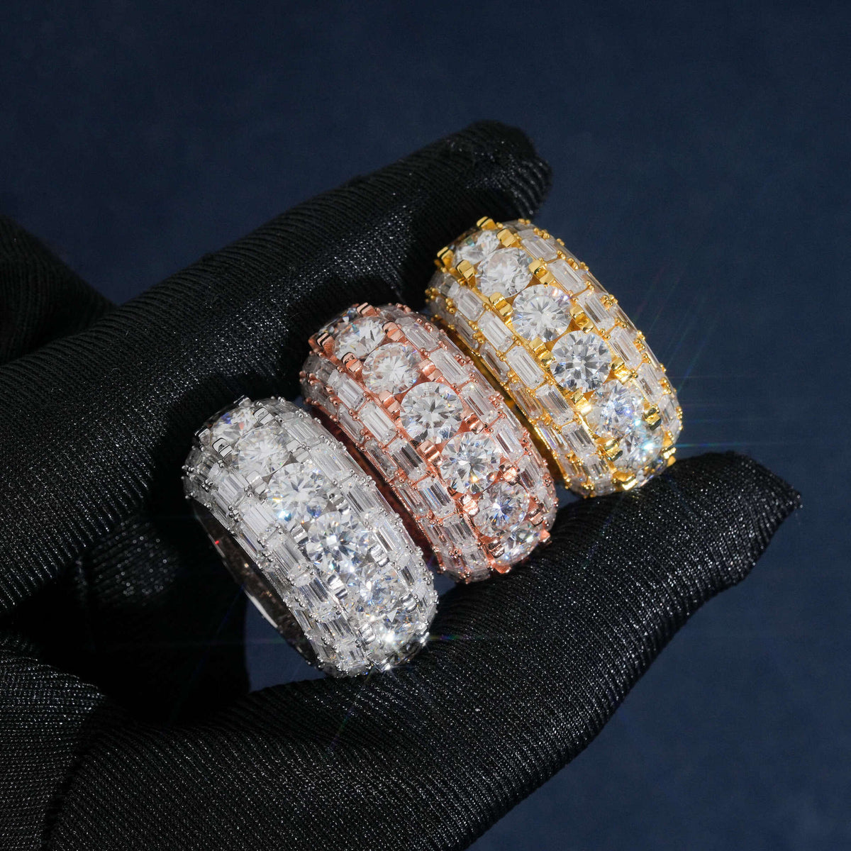 Hand wearing black glove holding S925 silver iced out round baguette moissanite 3-row band rings   