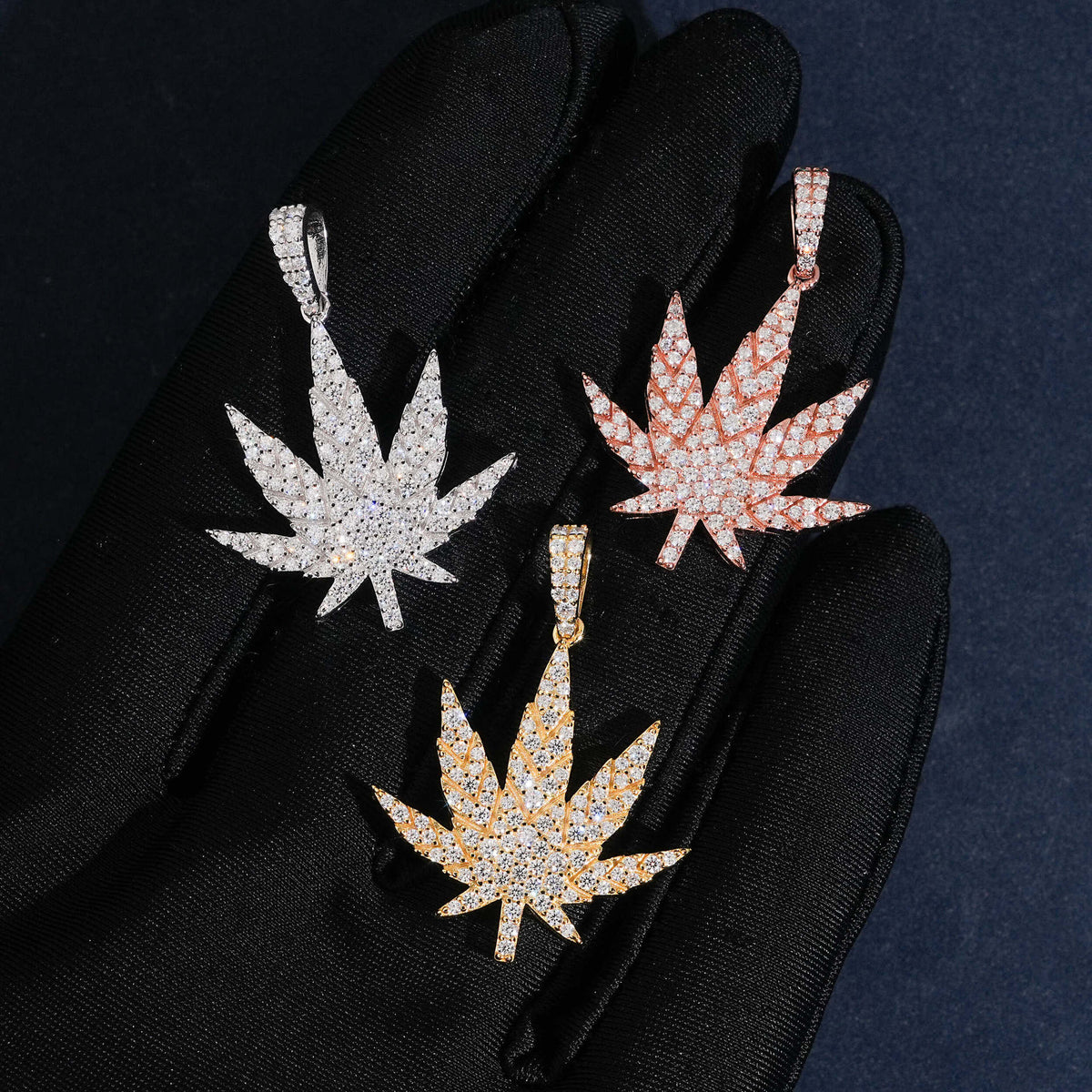 Hand wearing black glove holding 925 sterling silver iced out moissanite weed leaf hip hop pendants