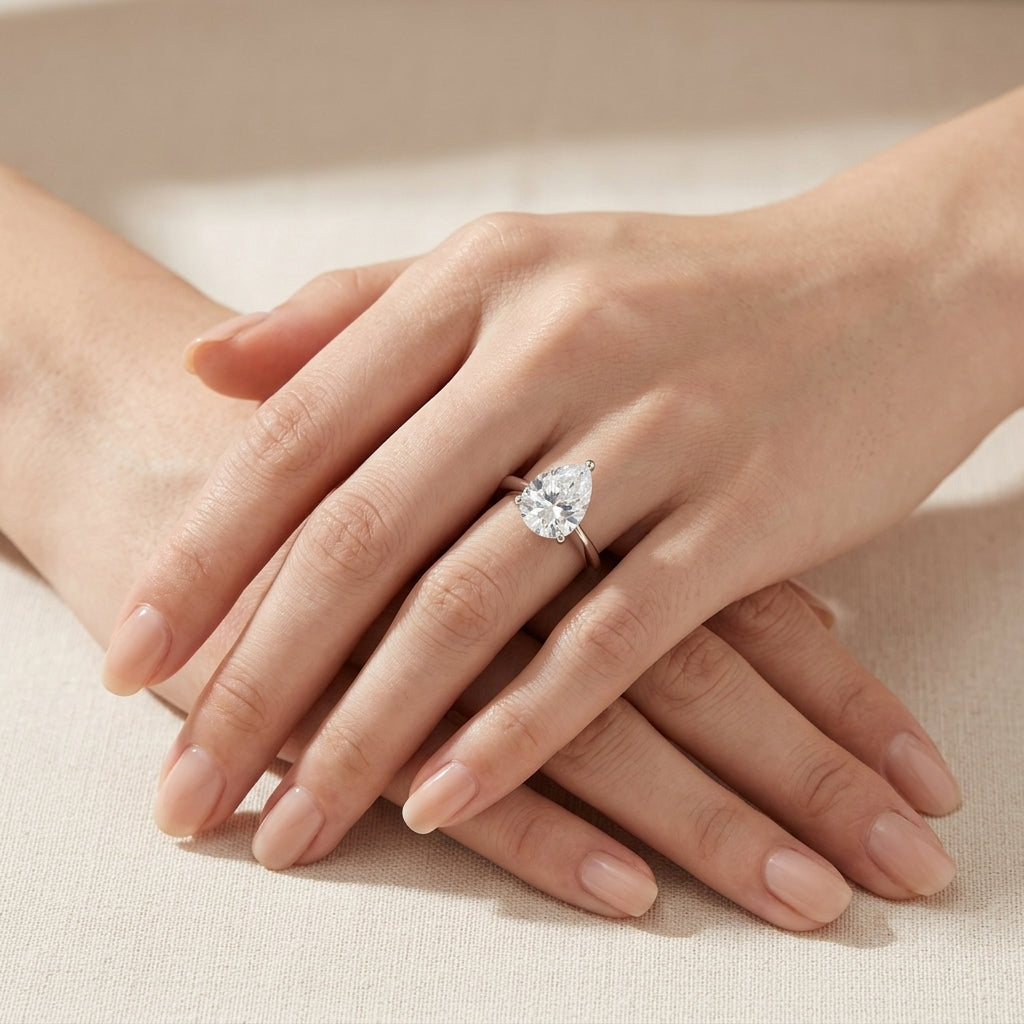 Close-up of hands styled with the unique horizontal teardrop moissanite solitaire ring.