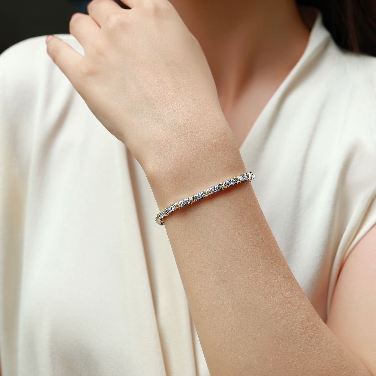 Hugs and kisses XO moissanite tennis bracelet displayed on light blue curved backdrop   