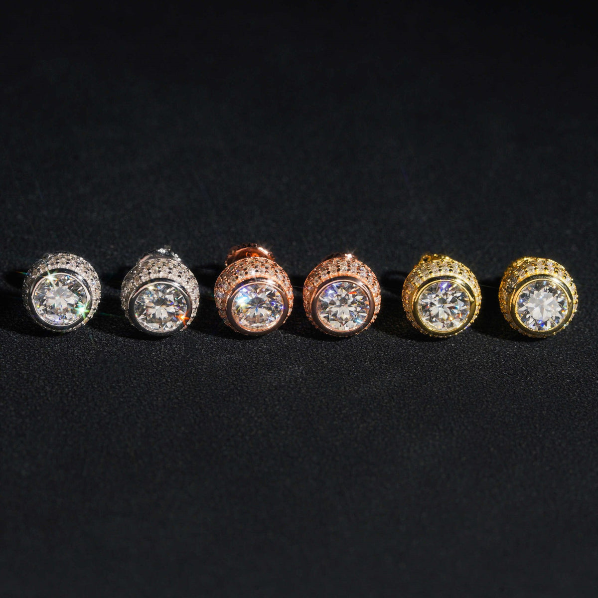 Three-tone iced out 3D bezel cylinder solitaire moissanite stud earrings with pave setting on dark surface