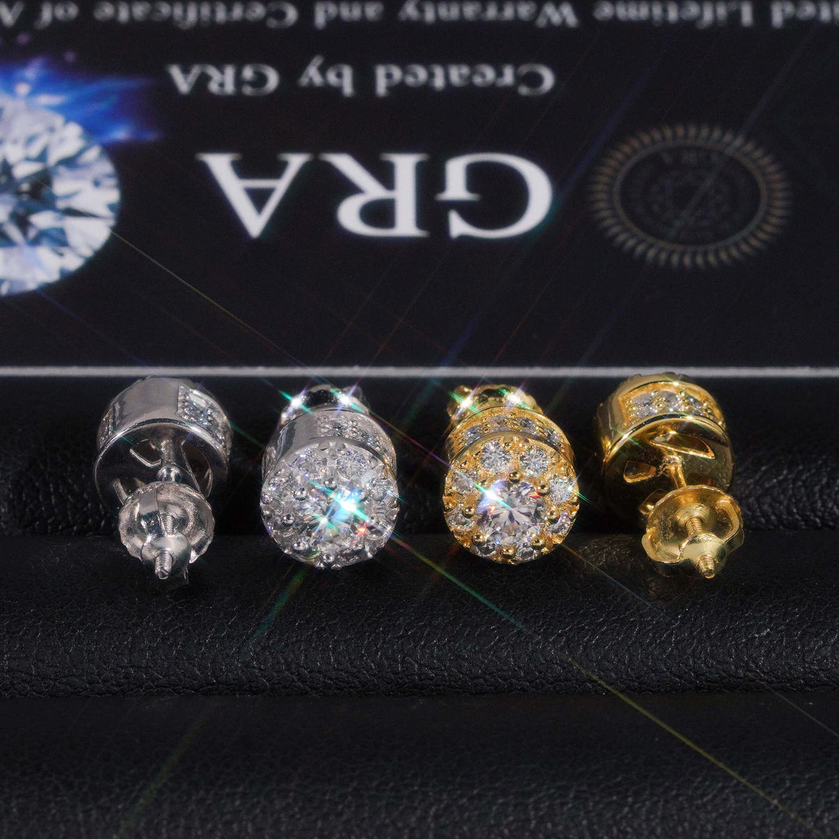Silver and gold iced out 3D crown cylinder solitaire moissanite stud earrings with pave setting in front of GRA certificate card