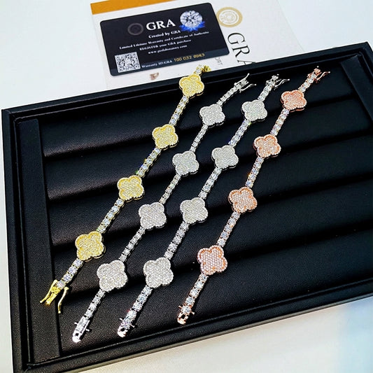 Iced out 3mm clover tennis moissanite bracelets in gold, silver, and rose gold on tray with GRA card