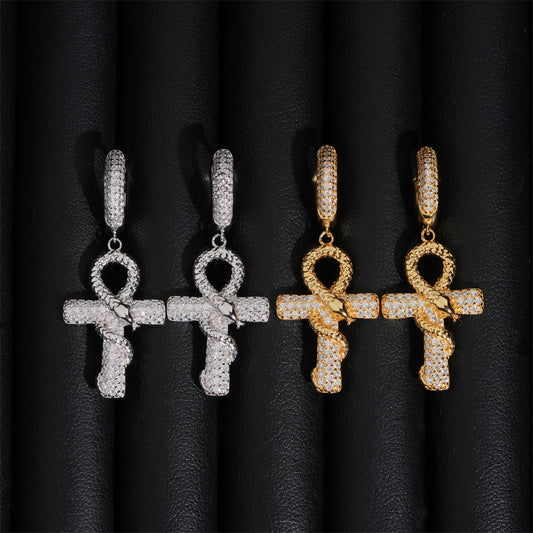 Gold and silver iced out ankh cross snake dangle huggie hoop moissanite earrings aligned on dark background