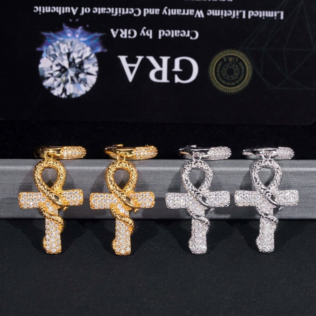 Iced out ankh cross snake dangle huggie hoop moissanite earrings in gold and silver in front of GRA card