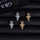Pair of silver and gold iced out ankh key of life cross moissanite stud earrings on dark leather background