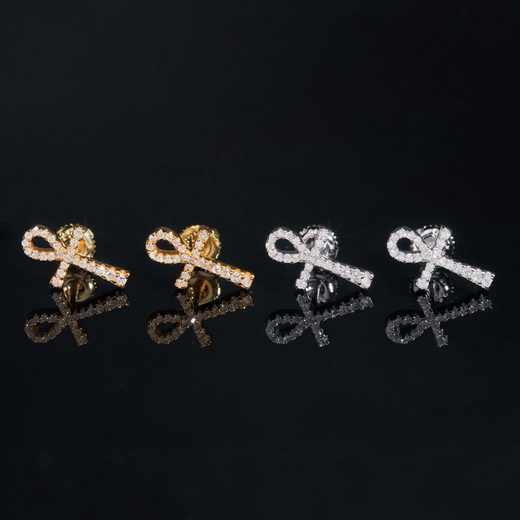 Iced out ankh key of life cross moissanite stud earrings in yellow gold and silver with reflections on black glass