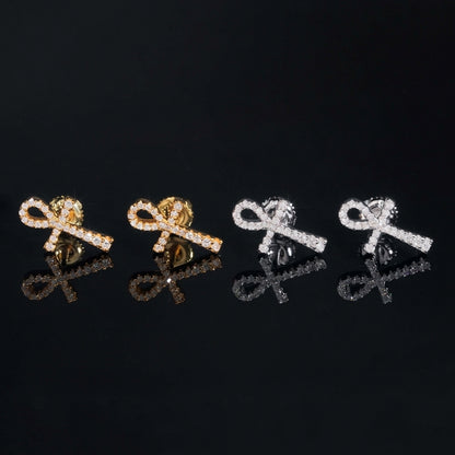 Iced out ankh key of life cross moissanite stud earrings in yellow gold and silver with reflections on black glass
