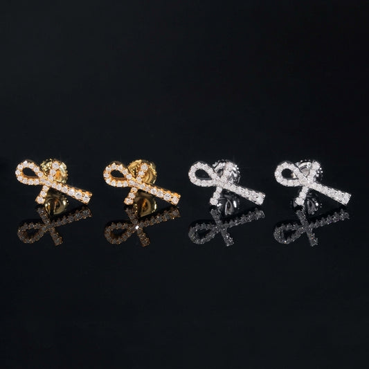 Iced out ankh key of life cross moissanite stud earrings in yellow gold and silver with reflections on black glass