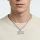 Editorial street style lookbook portrait of a model wearing an iced out ATM moissanite pendant with a cream sweater.