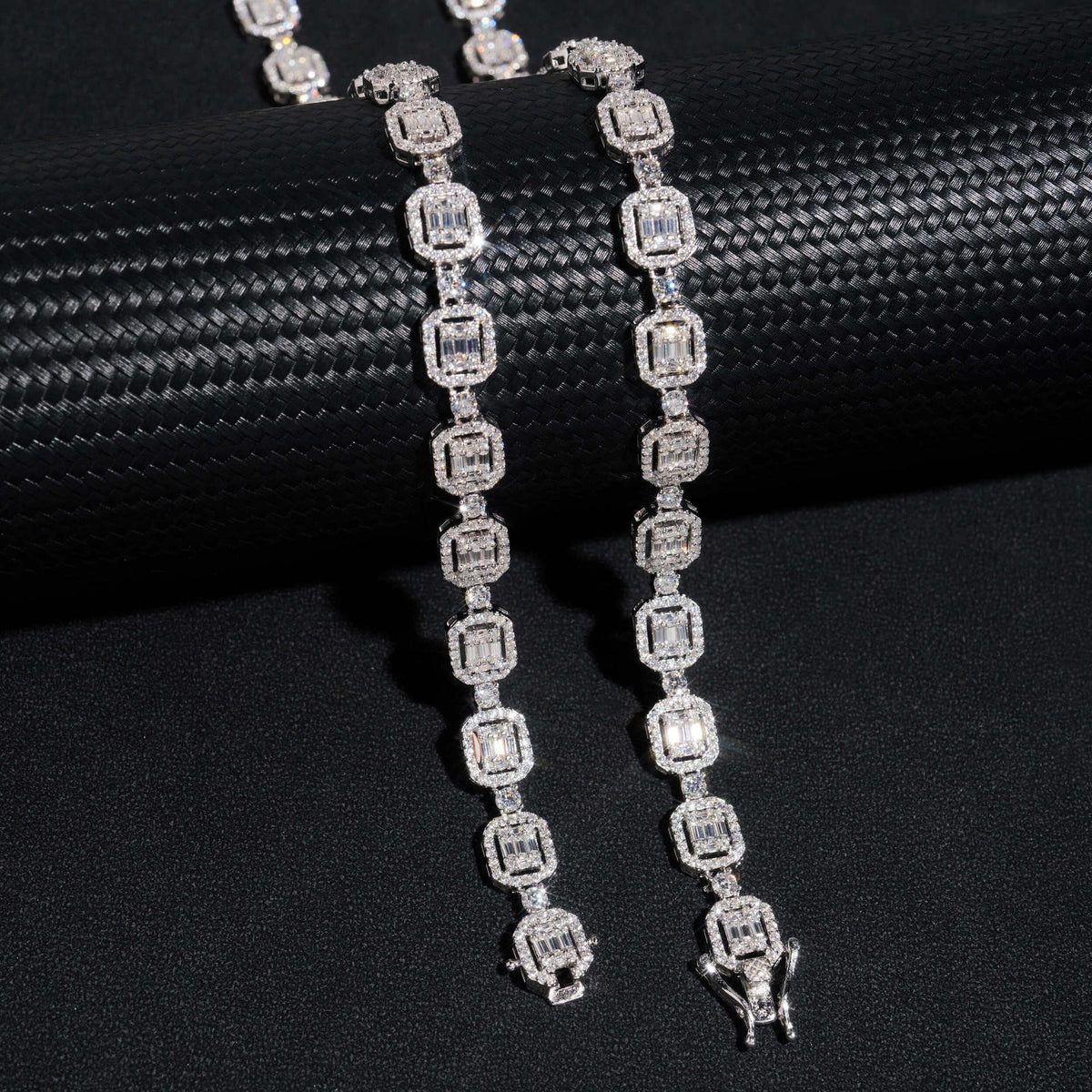 Silver iced out baguette halo and round alternating moissanite tennis chain and bracelet draped on cylinder stand