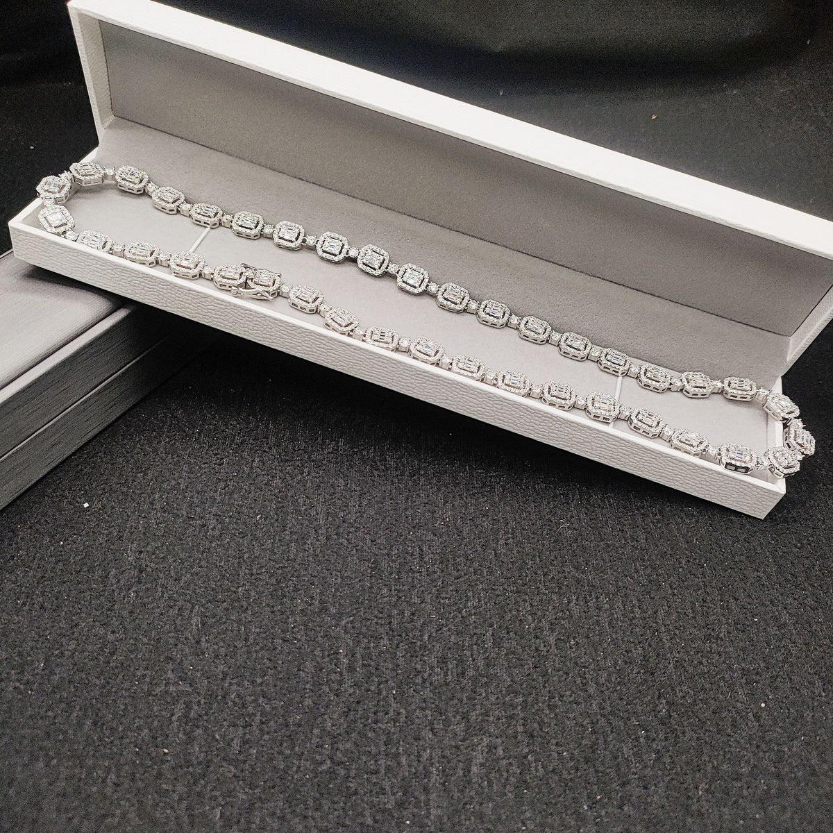 Silver iced out baguette halo and round alternating moissanite tennis chain displayed in box with GRA card
