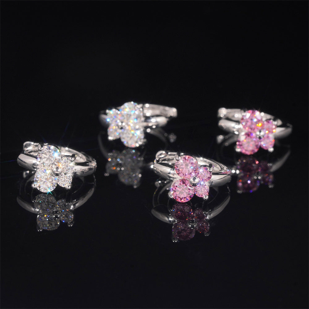Clear and pink iced out butterfly cluster huggie hoop moissanite earrings resting on reflective black surface   