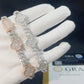Gloved hand holding rose gold and silver iced out clover cuban link moissanite bracelets with GRA card