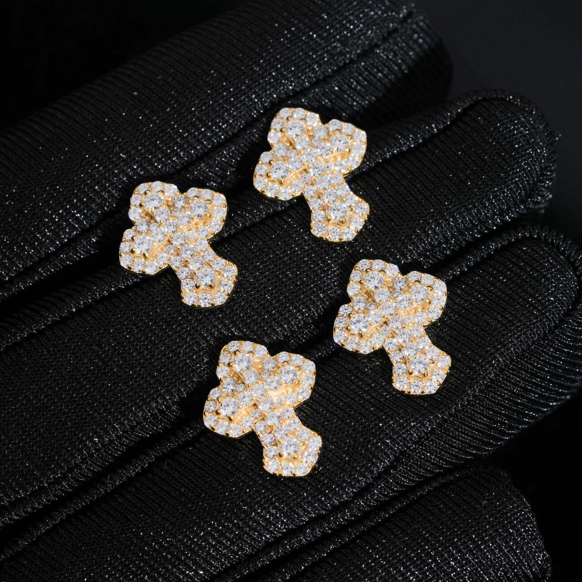 Yellow gold iced out clover floral micro-pave moissanite stud earrings displayed on black gloved hand   