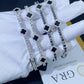 Gloved hand holding iced out black enamel clover tennis chain moissanite bracelets with double safety box clasp