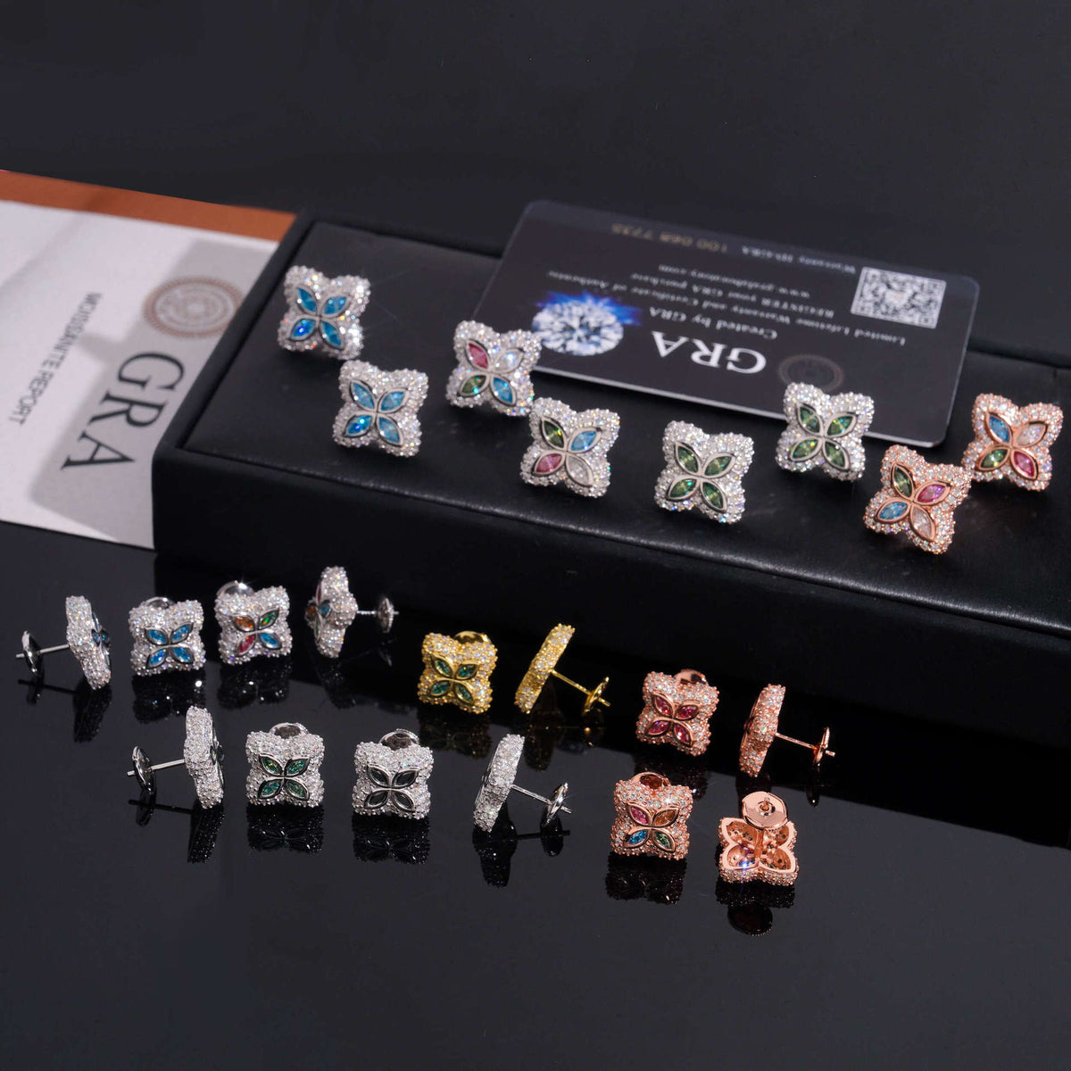 Multicolor iced out four-leaf clover moissanite stud earrings in box showing screw back posts and back view