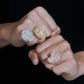 Person wearing iced out cross moissanite baguette statement rings in multiple gold finishes on hand