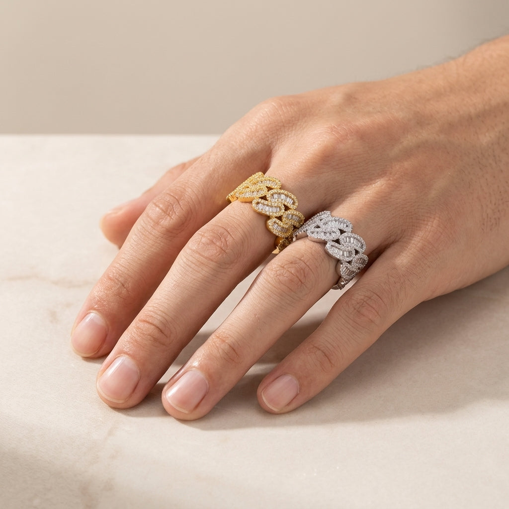 Person wearing silver and yellow gold iced out cuban link moissanite baguette rings on hand
