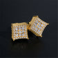 Pair of yellow gold iced out curved kite cluster moissanite stud earrings on dark surface