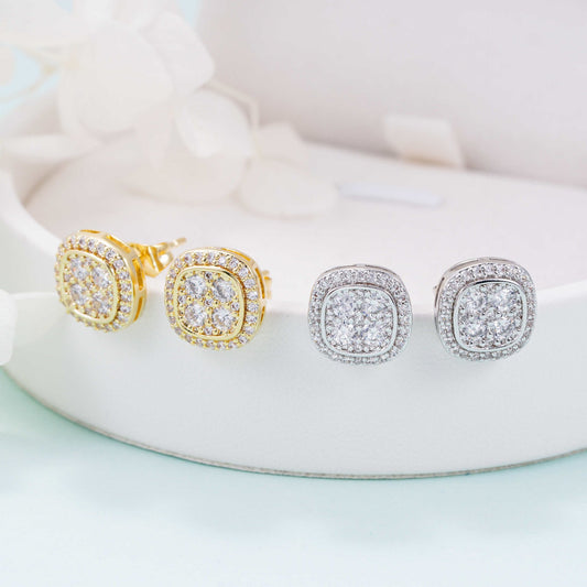 Iced out cushion square cluster moissanite stud earrings in gold and silver on white pedestal tray